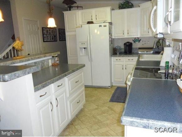 38802 Tyler Ave, Selbyville, DE 19975 - kitchen with white refrigerator with ice dispenser, a sink, white cabinetry, decorative light fixtures, and dark countertops