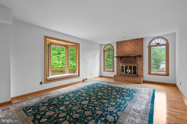 living area with plenty of natural light, wood finished floors, baseboards, and a fireplace