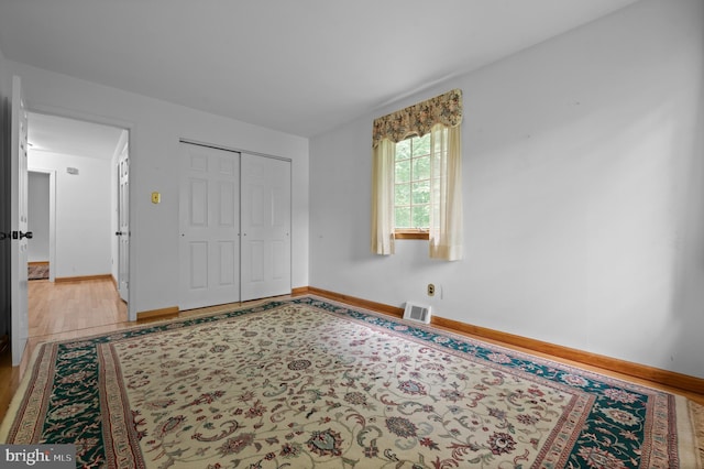 unfurnished bedroom with light wood finished floors, baseboards, and a closet