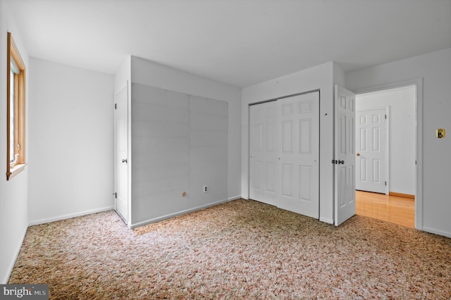unfurnished bedroom featuring carpet floors, baseboards, and a closet