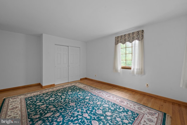 unfurnished bedroom with light wood-style floors, baseboards, and a closet