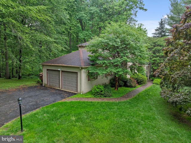garage with asphalt driveway and a forest view