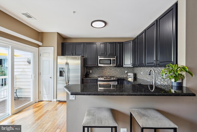 623 Main St Unit 623-B, Gaithersburg, MD 20878 - kitchen featuring appliances with stainless steel finishes, dark stone counters, a peninsula, light wood-style floors, and backsplash