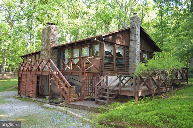 view of front of property with a chimney, a wooden deck, and stairs