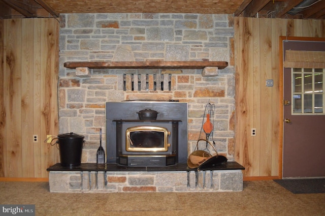 detailed view of wood walls, a wood stove, baseboards, and carpet floors