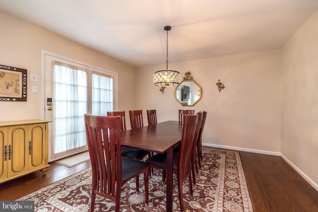 dining area featuring dark wood-type flooring, a chandelier, and baseboards