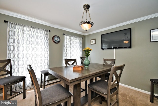 carpeted dining space with crown molding and baseboards