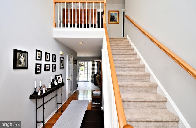 stairway featuring baseboards, a towering ceiling, and tile patterned floors