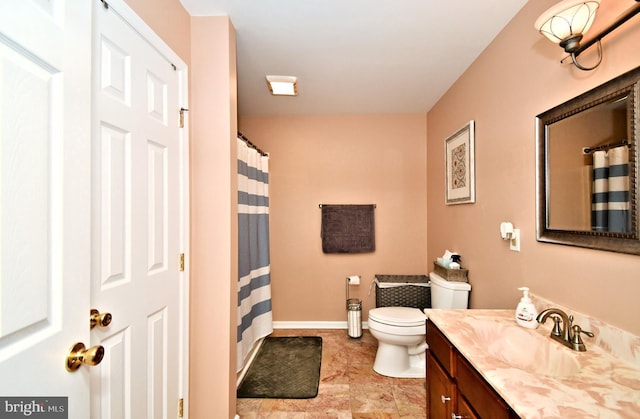 bathroom with toilet, vanity, and baseboards