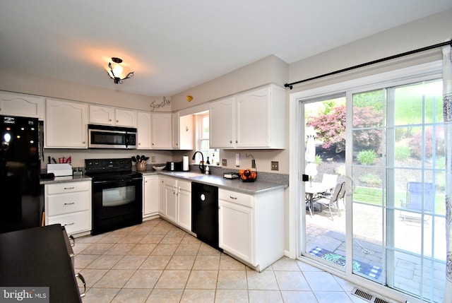 kitchen featuring black appliances, a sink, healthy amount of natural light, and light tile patterned floors