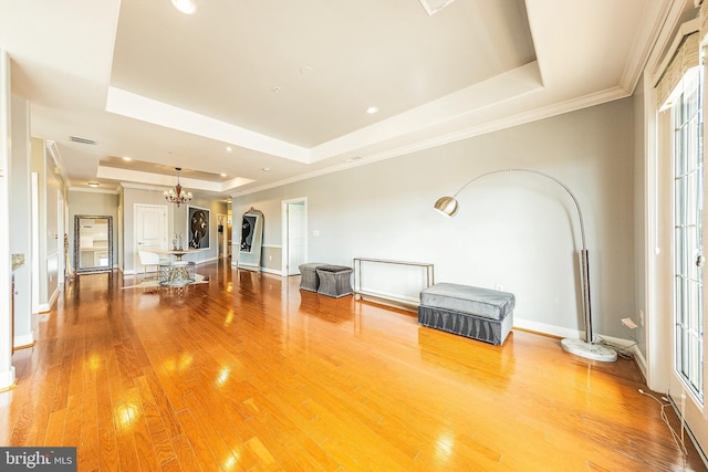 living room with a raised ceiling, a chandelier, plenty of natural light, light wood-style floors, and recessed lighting