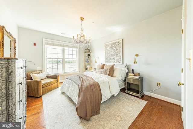 bedroom with a chandelier, wood finished floors, and baseboards