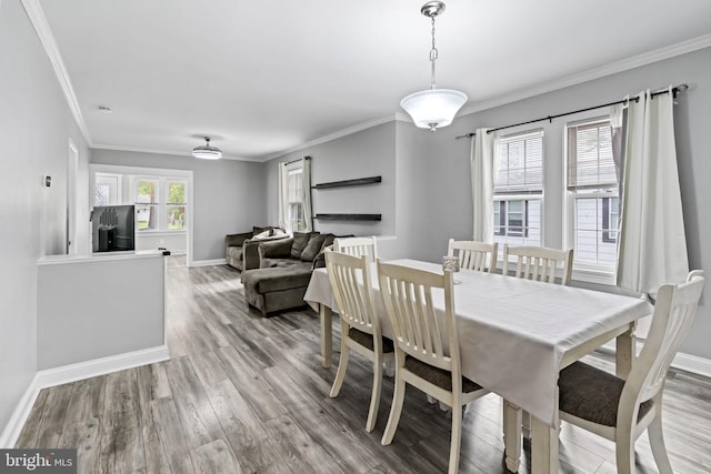 dining room featuring wood finished floors, baseboards, and crown molding