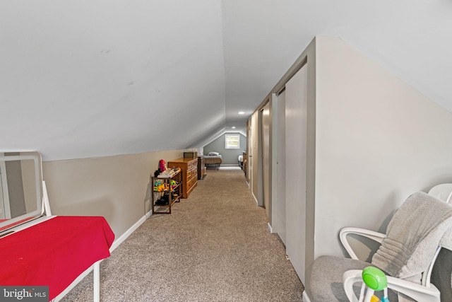 hall featuring lofted ceiling, carpet floors, and baseboards