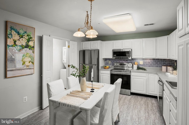 2021 Rudy Serra Dr Unit 1D, Eldersburg, MD 21784 - kitchen with appliances with stainless steel finishes, backsplash, light wood-style flooring, white cabinetry, and baseboards