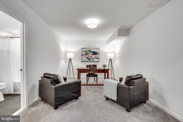 carpeted living room with baseboards and a desk