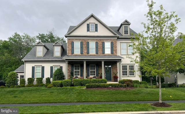 view of front facade with a porch, a front yard, and a shingled roof