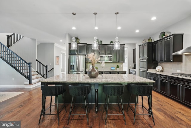 kitchen featuring stainless steel appliances, a breakfast bar, decorative backsplash, light stone counters, and recessed lighting