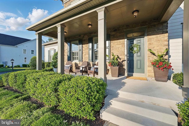 doorway to property featuring covered porch and stone siding