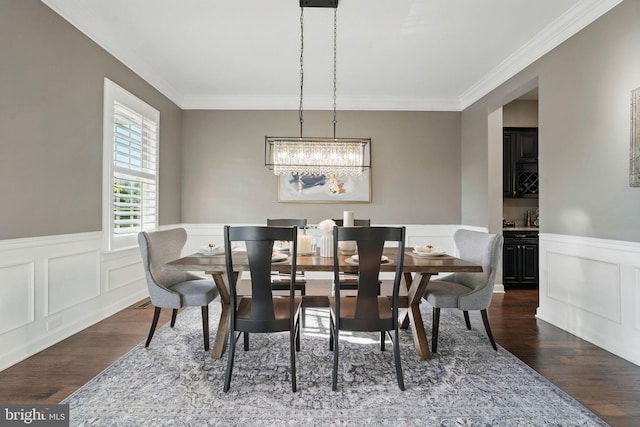 dining area with dark wood-style floors, ornamental molding, a chandelier, wainscoting, and a decorative wall