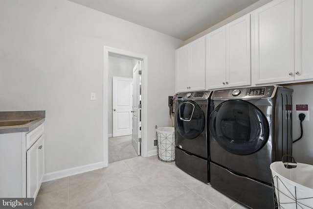 laundry room with washing machine and dryer, cabinet space, light tile patterned floors, and baseboards