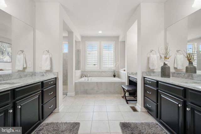full bathroom with tile patterned floors, two vanities, a garden tub, and recessed lighting
