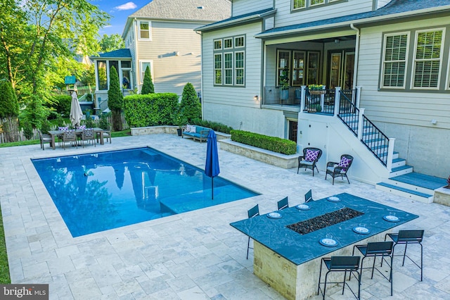 view of swimming pool featuring stairs, a patio area, a sunroom, and outdoor dining space