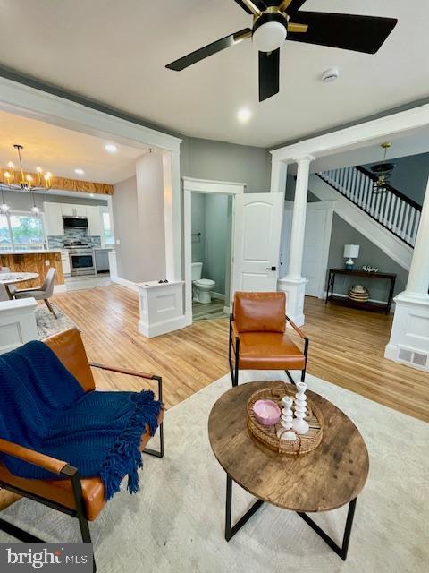 25 Elmont Ave, Baltimore, MD 21206 - living room featuring decorative columns, light wood-type flooring, ceiling fan, and stairs