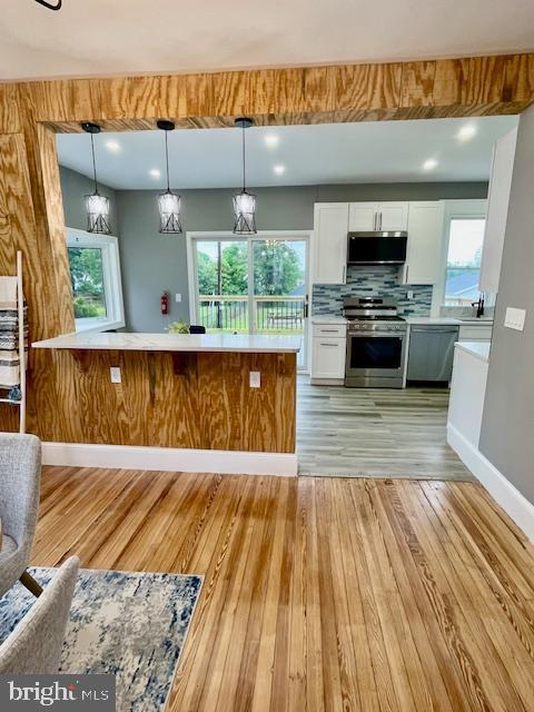 25 Elmont Ave, Baltimore, MD 21206 - kitchen with appliances with stainless steel finishes, white cabinets, light wood-type flooring, light countertops, and decorative light fixtures