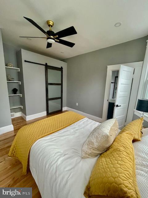 25 Elmont Ave, Baltimore, MD 21206 - bedroom with a barn door, wood finished floors, baseboards, and ceiling fan