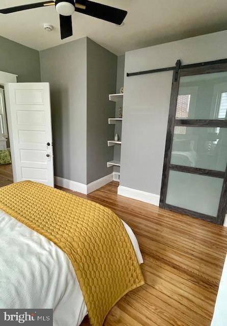 25 Elmont Ave, Baltimore, MD 21206 - bedroom with baseboards, wood finished floors, a barn door, and ceiling fan