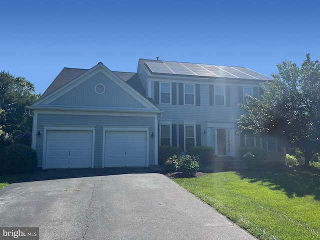 colonial home with a front lawn, driveway, and a garage