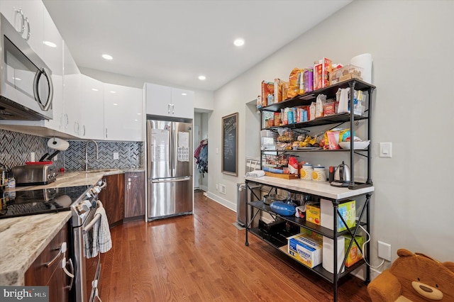 1322 N Hollywood St, Philadelphia, PA 19121 - kitchen with stainless steel appliances, wood finished floors, backsplash, white cabinetry, and light stone countertops