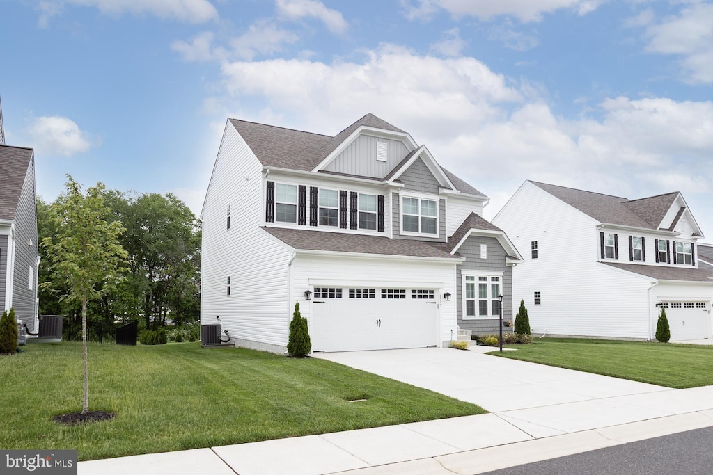 view of front of home featuring cooling unit, driveway, a garage, and a front yard
