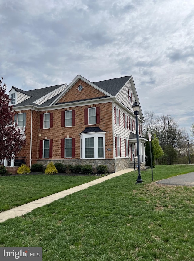 view of front of house featuring a front lawn, stone siding, and brick siding
