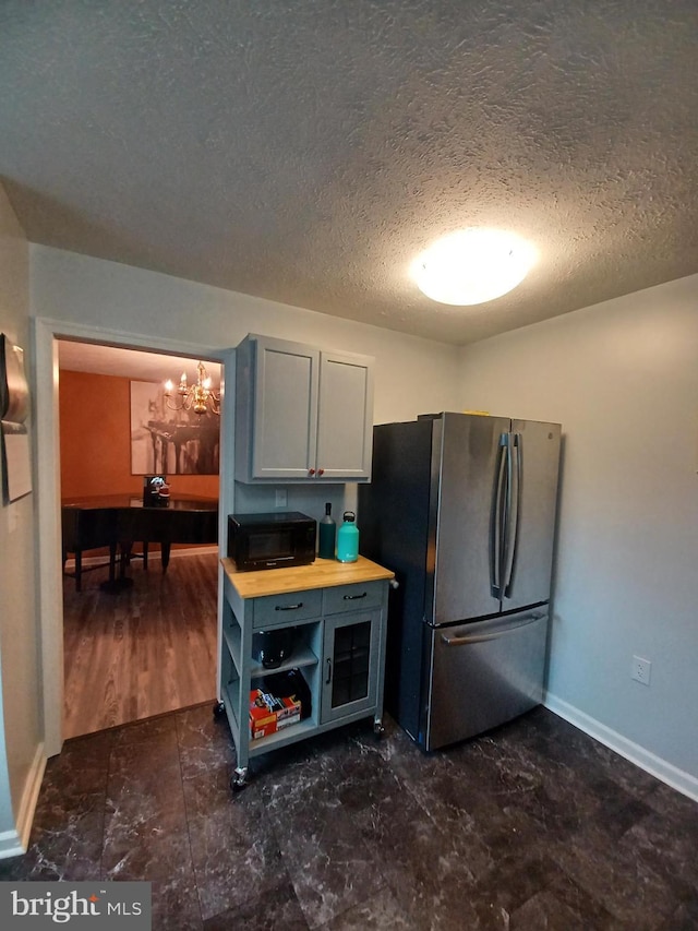 189 Columbia Dr, Kearneysville, WV 25430 - kitchen featuring freestanding refrigerator, a chandelier, black microwave, a textured ceiling, and baseboards