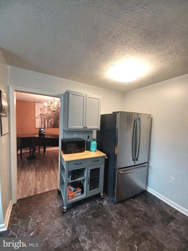 189 Columbia Dr, Kearneysville, WV 25430 - kitchen with freestanding refrigerator, a textured ceiling, black microwave, baseboards, and a chandelier