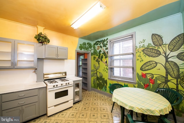 3632 Midvale Ave, Philadelphia, PA 19129 - kitchen featuring white range with gas stovetop, gray cabinets, light floors, light countertops, and glass insert cabinets