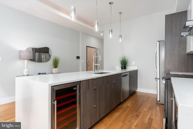 1125 Morse St NE Unit 2, Washington, DC 20002 - kitchen featuring beverage cooler, appliances with stainless steel finishes, a peninsula, light wood-style flooring, and baseboards