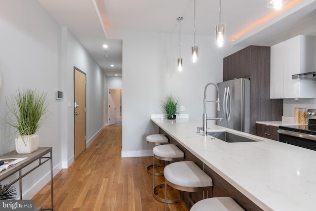 1125 Morse St NE Unit 2, Washington, DC 20002 - kitchen featuring stainless steel appliances, modern cabinets, a sink, a kitchen bar, and light wood-style flooring