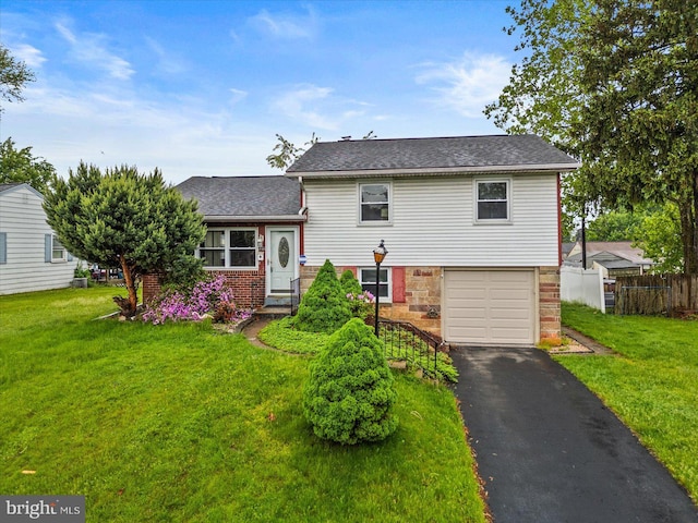 129 Henry Rd, Enola, PA 17025 - tri-level home with a garage, asphalt driveway, a shingled roof, and brick siding