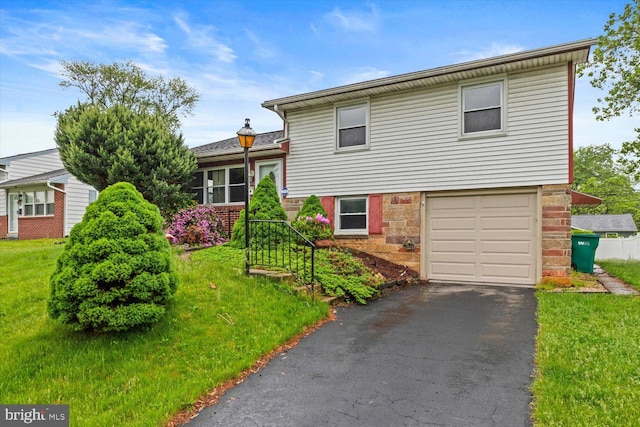 129 Henry Rd, Enola, PA 17025 - split level home with an attached garage, asphalt driveway, stone siding, and a front lawn