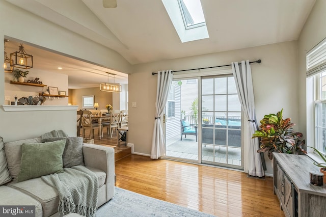 living area with lofted ceiling, hardwood / wood-style flooring, a skylight, and baseboards