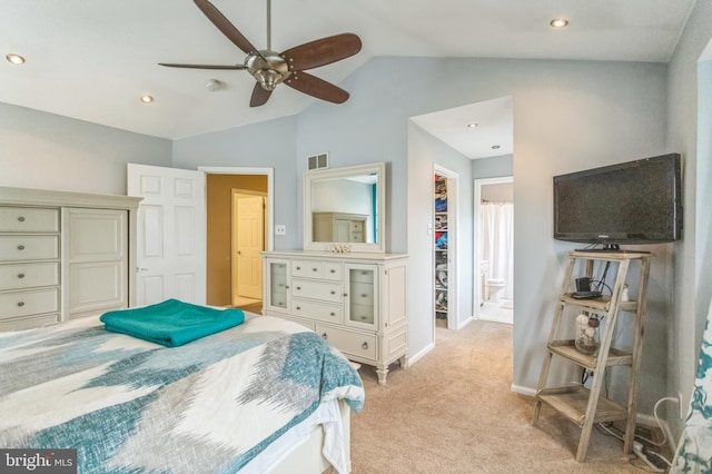 bedroom with a closet, lofted ceiling, light carpet, a walk in closet, and baseboards