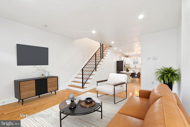 living area featuring stairs, light wood-style floors, baseboards, and recessed lighting