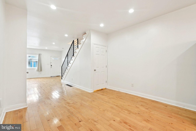 unfurnished room featuring stairway, light wood-type flooring, baseboards, and recessed lighting
