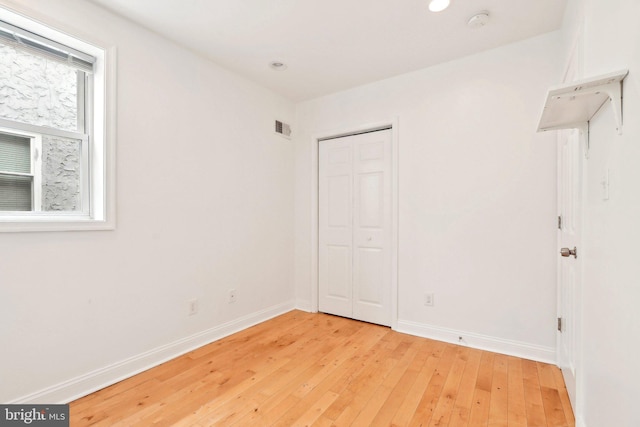 unfurnished bedroom featuring light wood finished floors, baseboards, a closet, and recessed lighting