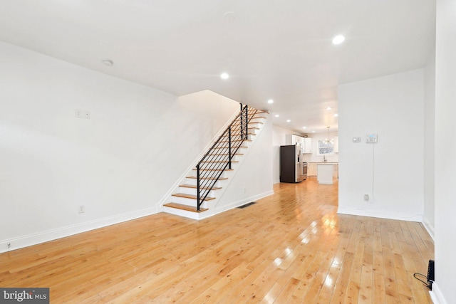 unfurnished living room with light wood-style flooring, stairs, baseboards, and recessed lighting