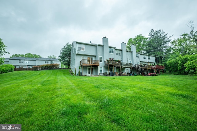 back of property with a chimney, a deck, and a yard