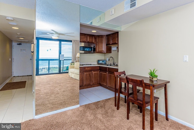 10900 Coastal Hwy Unit 209, Ocean City, MD 21842 - kitchen with light carpet, stainless steel microwave, a ceiling fan, light tile patterned flooring, and a sink